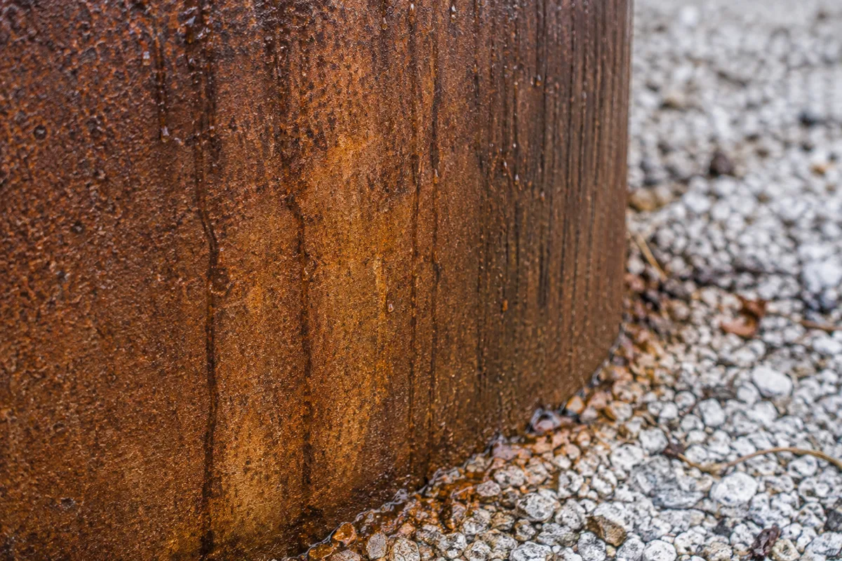 Gros plan sur la paroi patinée d&rsquo;un brasero en acier corten et ses coulures d&rsquo;oxyde